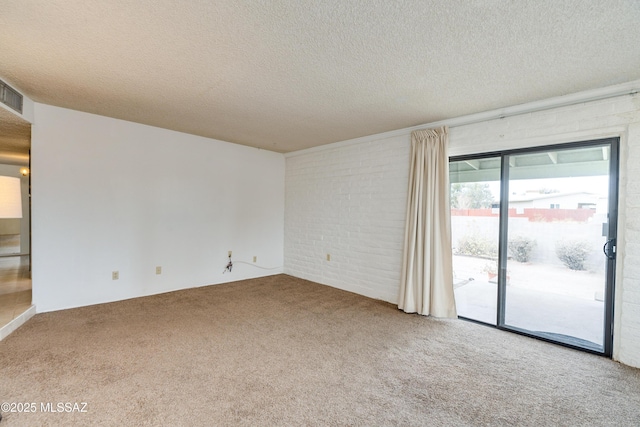 carpeted spare room featuring a textured ceiling and brick wall