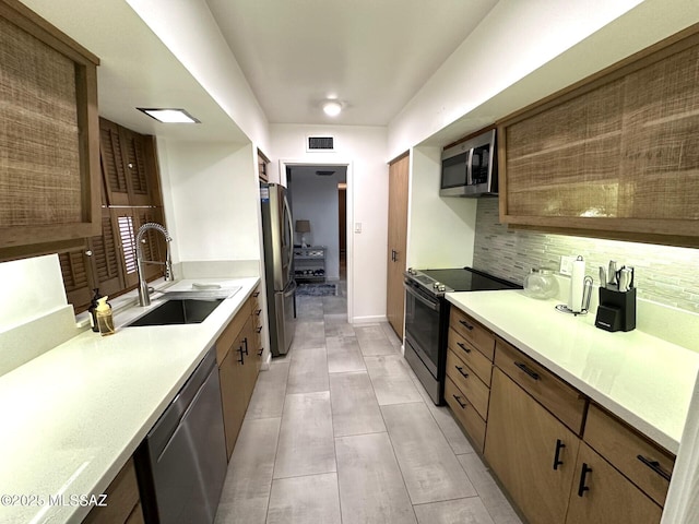 kitchen with tasteful backsplash, appliances with stainless steel finishes, and sink