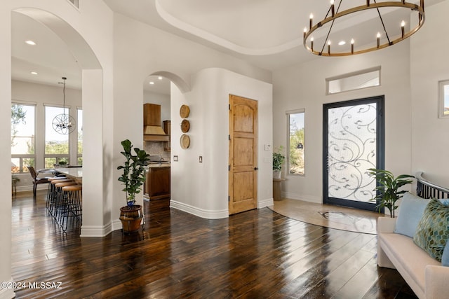 foyer entrance featuring an inviting chandelier, a raised ceiling, and dark wood-type flooring