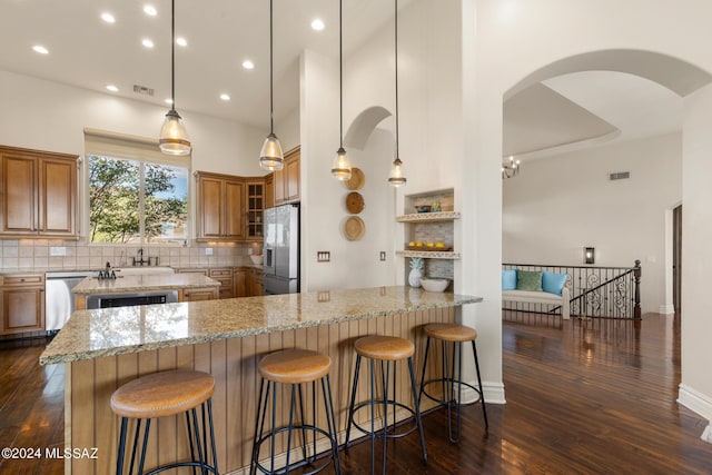 kitchen featuring tasteful backsplash, hanging light fixtures, kitchen peninsula, dishwasher, and refrigerator with ice dispenser