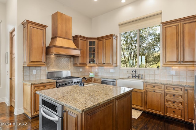 kitchen with dark hardwood / wood-style floors, an island with sink, sink, custom exhaust hood, and light stone countertops