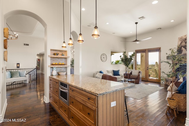 kitchen featuring dark hardwood / wood-style flooring, decorative light fixtures, oven, and a breakfast bar