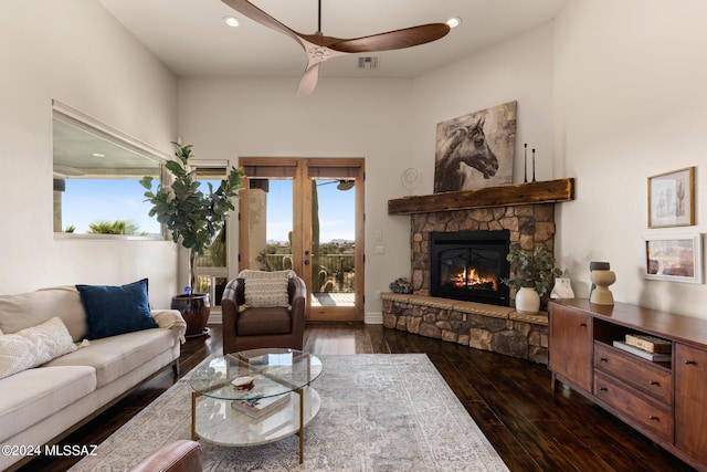 living room with dark wood-type flooring, ceiling fan, a fireplace, and french doors