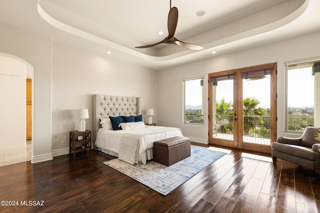 bedroom featuring access to exterior, ceiling fan, a raised ceiling, dark wood-type flooring, and french doors