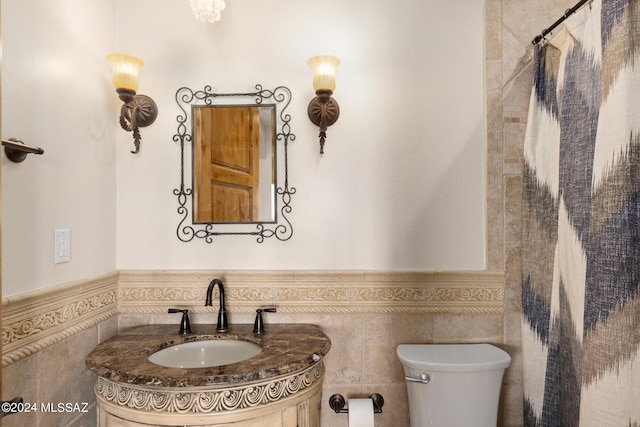 bathroom with vanity, tile walls, and toilet