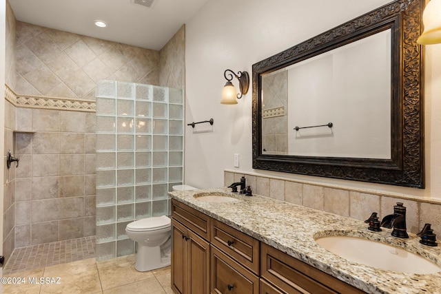 bathroom with tiled shower, vanity, toilet, and tile patterned floors