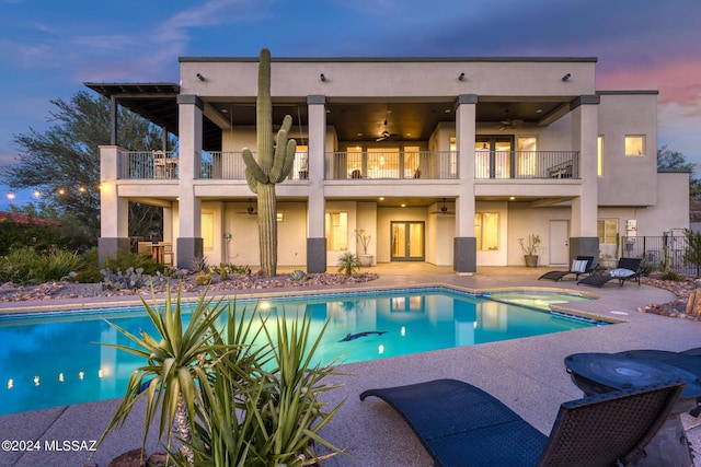 pool at dusk with a patio, ceiling fan, and an in ground hot tub