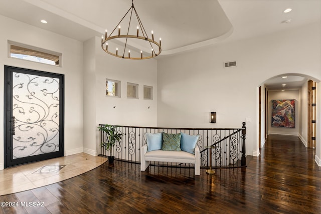 entrance foyer with a raised ceiling, hardwood / wood-style floors, and an inviting chandelier