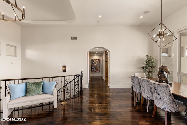 dining area with dark wood-type flooring and an inviting chandelier