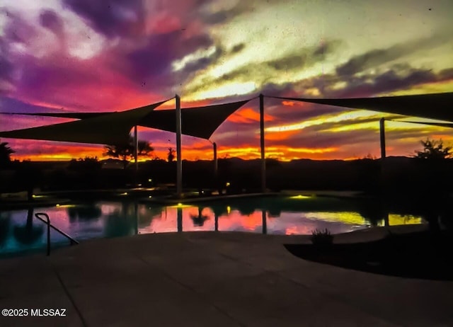 pool at dusk featuring a water view