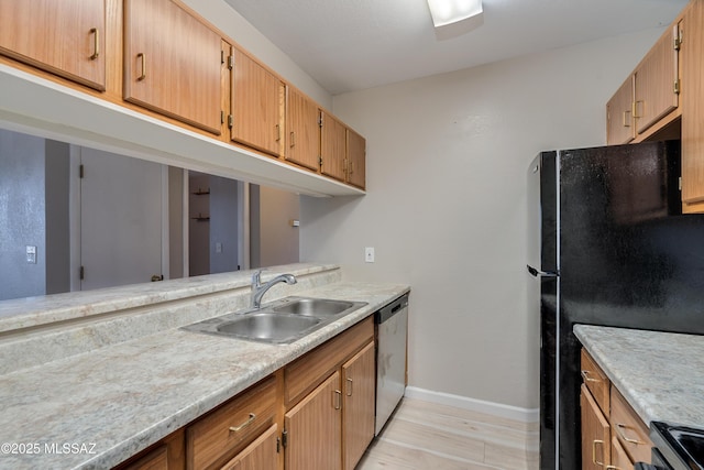 kitchen with electric range oven, dishwasher, sink, black fridge, and light wood-type flooring