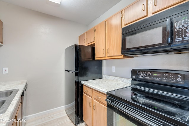 kitchen with light brown cabinets, light hardwood / wood-style floors, and black appliances