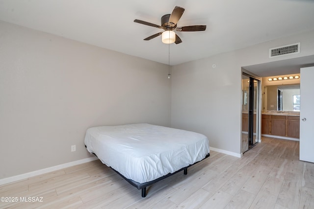 bedroom featuring light hardwood / wood-style floors, ceiling fan, and ensuite bathroom