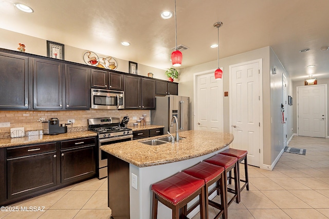 kitchen with a kitchen bar, sink, decorative light fixtures, an island with sink, and stainless steel appliances