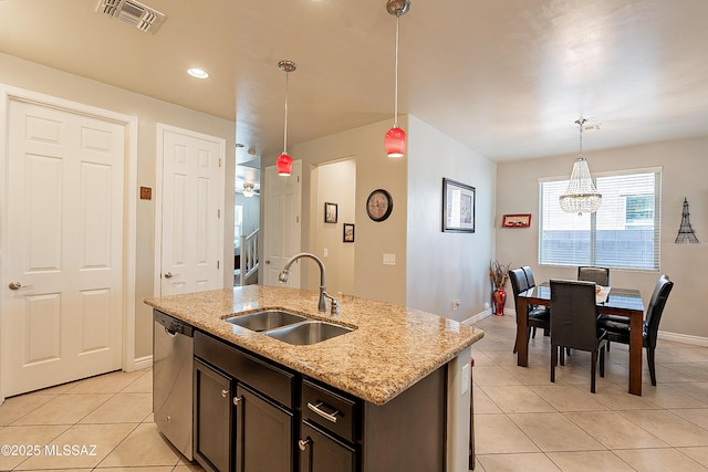 kitchen with decorative light fixtures, sink, a kitchen island with sink, stainless steel dishwasher, and light stone counters