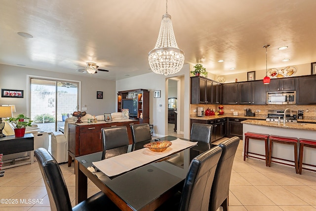 dining area featuring light tile patterned flooring, sink, and ceiling fan with notable chandelier