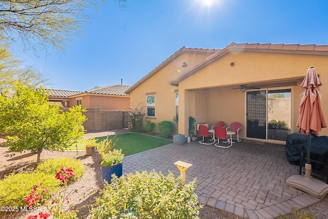 rear view of house featuring ceiling fan and a patio area