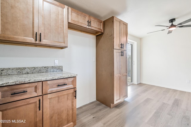 kitchen featuring ceiling fan, light stone countertops, and light hardwood / wood-style floors