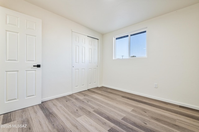 unfurnished bedroom with light hardwood / wood-style flooring and a closet