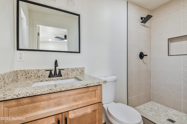 bathroom featuring vanity, ceiling fan, toilet, and tiled shower