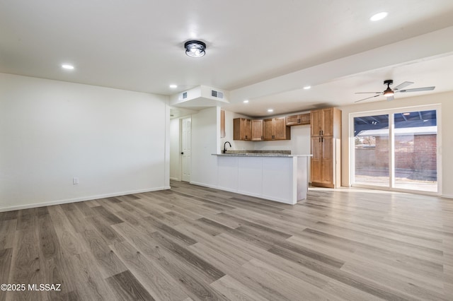 unfurnished living room featuring sink, ceiling fan, and light hardwood / wood-style flooring