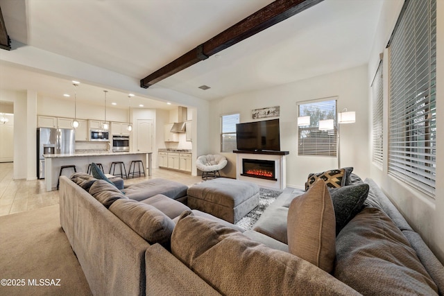 living room with beamed ceiling and light carpet