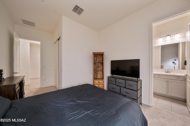 bedroom featuring light carpet, visible vents, a sink, and ensuite bathroom