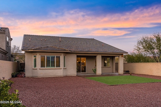 back house at dusk featuring a patio