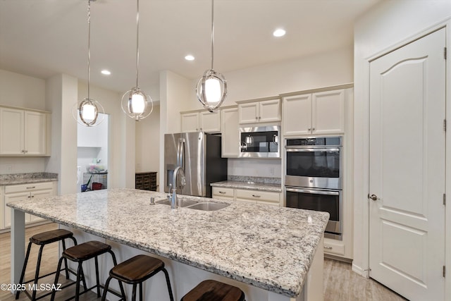 kitchen featuring recessed lighting, stainless steel appliances, a breakfast bar, a sink, and light wood-type flooring