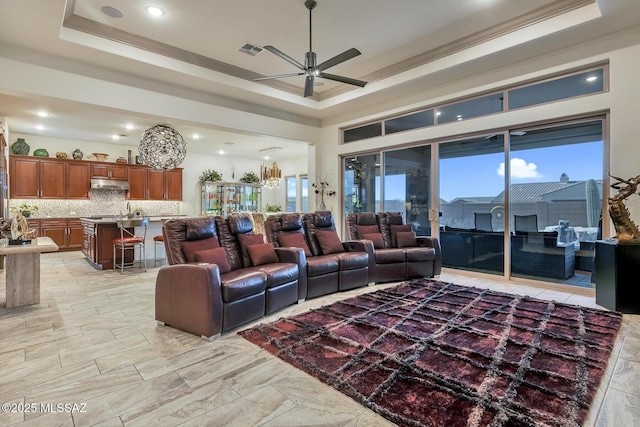 living room featuring ornamental molding, a raised ceiling, visible vents, and a ceiling fan