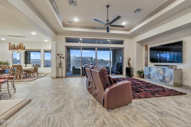 living room featuring ceiling fan with notable chandelier, visible vents, a tray ceiling, and ornamental molding