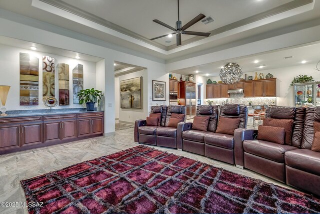 living room featuring marble finish floor, crown molding, a raised ceiling, visible vents, and ceiling fan