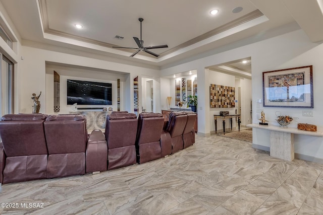 home theater room with a ceiling fan, baseboards, marble finish floor, a raised ceiling, and crown molding