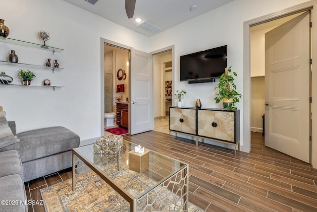 living area with baseboards, wood tiled floor, visible vents, and a ceiling fan