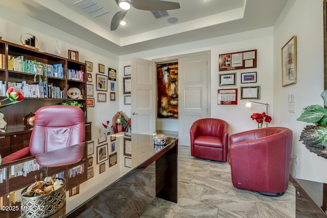 sitting room with ceiling fan, visible vents, and a raised ceiling