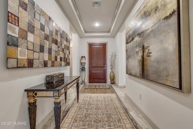 entryway with a tray ceiling, visible vents, and baseboards