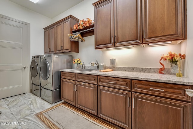 clothes washing area featuring cabinet space, washer and dryer, and a sink