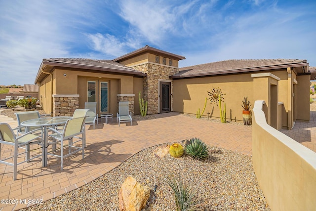 back of house featuring stone siding, a patio, and stucco siding