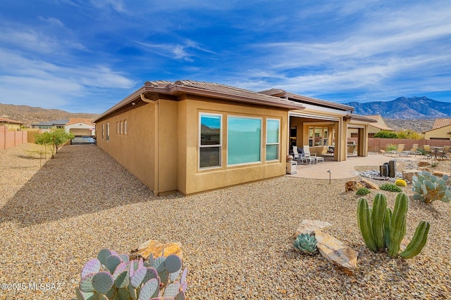 back of house with a patio area, a fenced backyard, a mountain view, and stucco siding