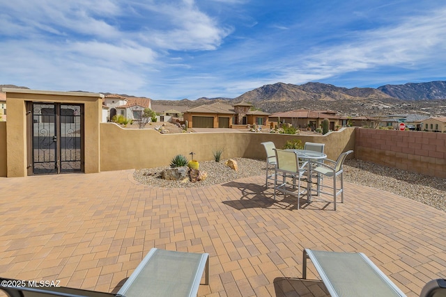 view of patio featuring outdoor dining area, a residential view, a fenced backyard, and a mountain view