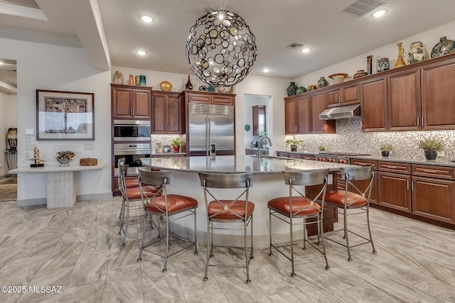 kitchen featuring appliances with stainless steel finishes, an island with sink, a sink, and visible vents