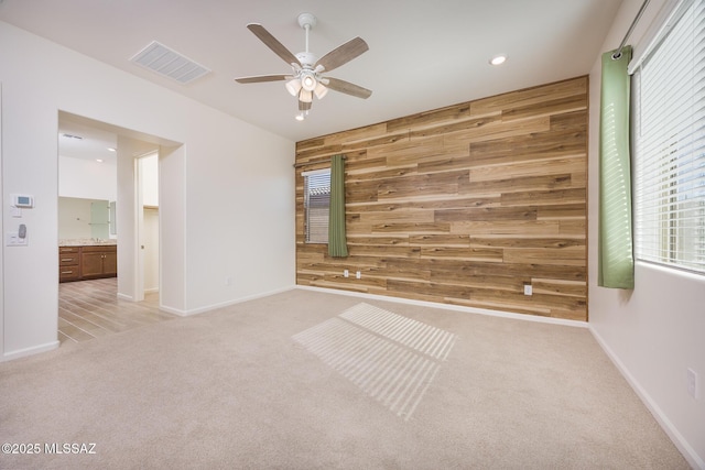 carpeted empty room with ceiling fan and wooden walls