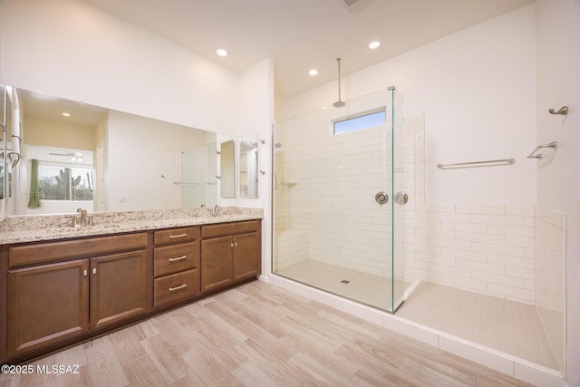 bathroom featuring vanity, wood-type flooring, and a tile shower