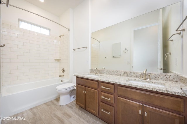 full bathroom with tiled shower / bath combo, vanity, hardwood / wood-style flooring, and toilet