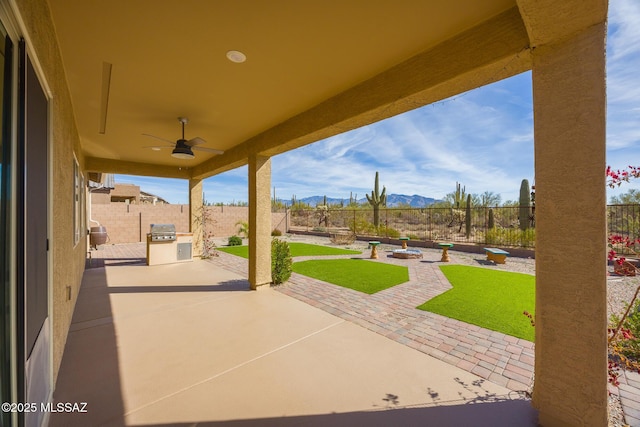 view of patio / terrace with ceiling fan, a mountain view, and area for grilling