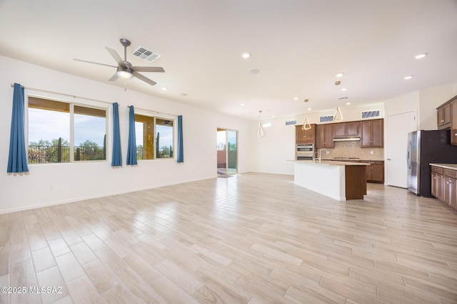 unfurnished living room with a wealth of natural light, ceiling fan, and light wood-type flooring