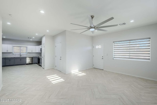 unfurnished living room with ceiling fan, light parquet flooring, and sink