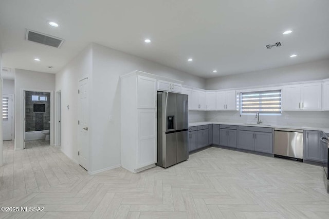 kitchen featuring gray cabinetry, sink, white cabinetry, and stainless steel appliances