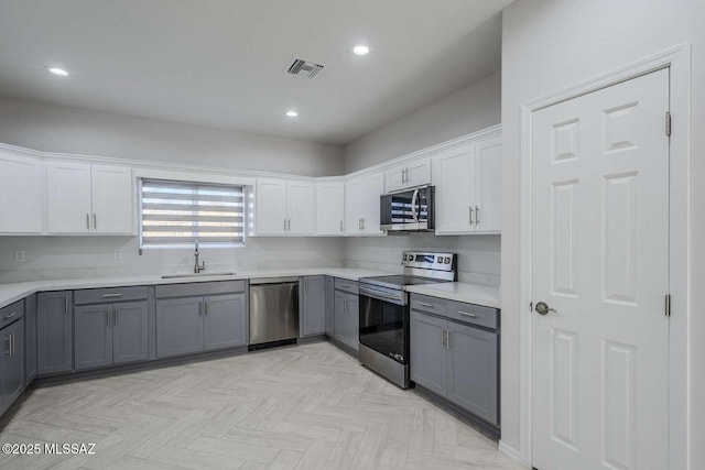 kitchen featuring gray cabinets, white cabinetry, appliances with stainless steel finishes, and sink