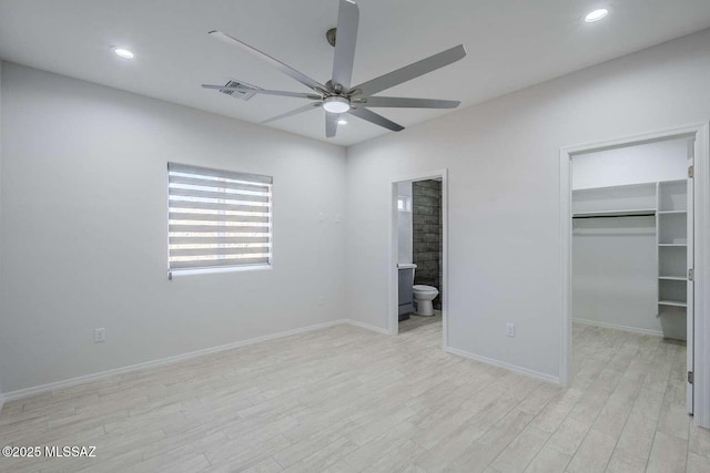 unfurnished bedroom featuring a spacious closet, light hardwood / wood-style floors, a closet, and ensuite bathroom